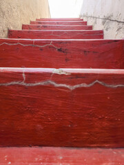 Stock photo of old concrete staircase painted with maroon color, light yellow color painted wall beside the staircase,Picture captured under natural light at Gulbarga, Karnataka, India.selective focus