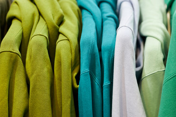 multi-colored sweatshirts on hangers in the store. Bright colorful sweatshirts hang in a fashion...