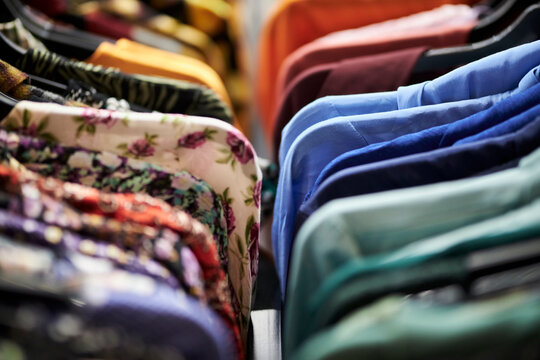 women's multi-colored blouses and shirts hang on hangers in a clothing store. women's spring and summer colorful blouses and shirts hang on hangers in a clothing store
