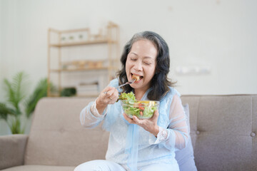 Portrait of an elderly Asian woman taking care of her health by eating salad.