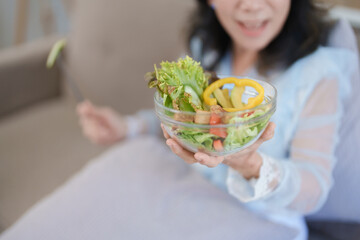 Portrait of an elderly Asian woman taking care of her health by eating salad.