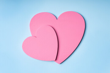 Valentine's Day. Pink wooden hearts on a pastel blue background. Festive background.