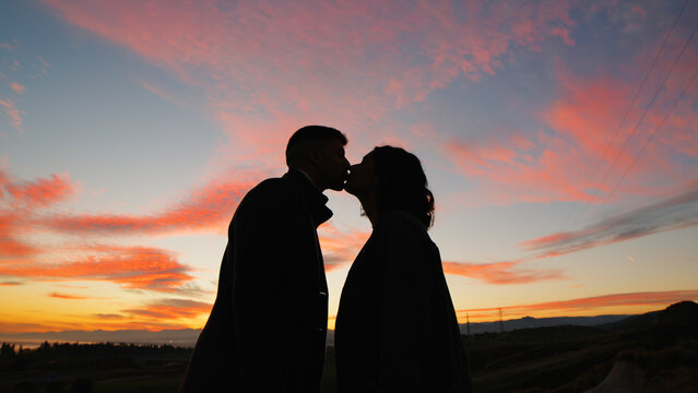 Silhouette of couple kiss against the orange sunset