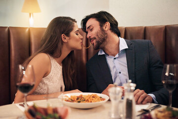 Love, kiss and spaghetti with couple in restaurant sharing for romance, valentines day and date. Bonding, smile and celebration with man and woman with pasta at table for fine dining, wine and cute