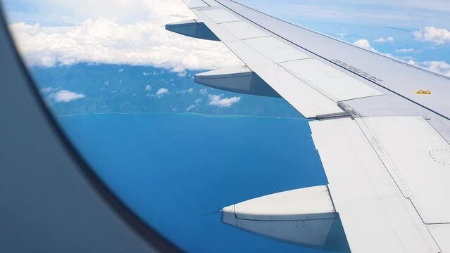 Landscape of Timor Leste coastline, beautiful blue ocean, and view of wing from commercial airplane airplane window flying into capital Dili, East Timor in Southeast Asia