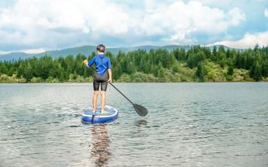 active teen girl paddling a sup board on a river or lake, natural background, active healthy sporty lifestyle. High quality photo