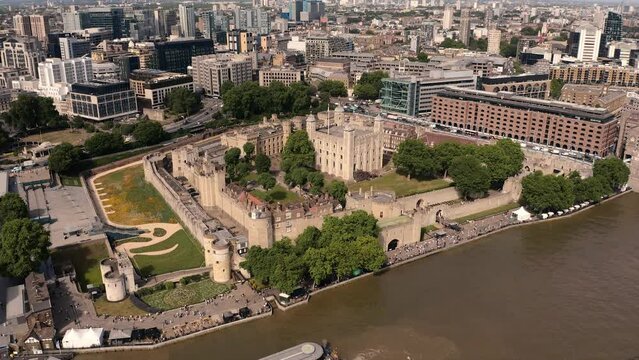 Drone shot pushing into The Tower of London on a hot Summers day over the River Thames on a busy day, bustling with tourists