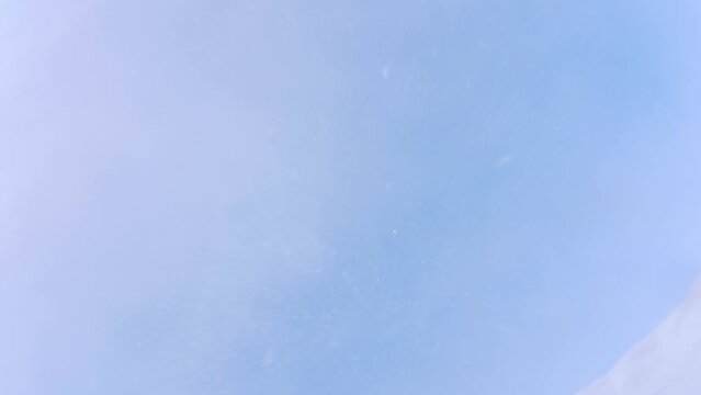 Slow motion. Snowboarder doing a frontflip over camera and snow falling