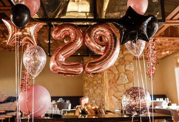 Restaurante room decorated for a birthday party with pink, black and transparent baloons of...