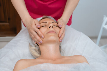 Fototapeta na wymiar Face massage. Young woman getting spa massage treatment at beauty spa salon. Skin and body care. Facial beauty treatment