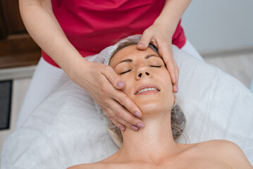 Fototapeta na wymiar Face massage. Young woman getting spa massage treatment at beauty spa salon. Skin and body care. Facial beauty treatment