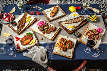 Food Table Celebration Delicious Party Meal Concept. A lot of food on the  table: fish, salmon, trout, meat, chicken, lamb, beef.  Foodset from Georgian dishes. Caucasian food