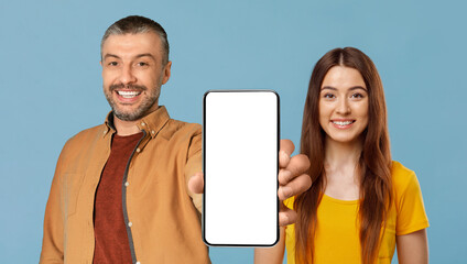 Smiling Man And Woman Demonstrating Blank Smartphone While Posing On Blue Background