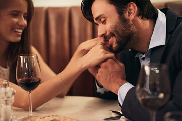Hand, kiss and date with a couple in a restaurant on a night out together for love, fine dining or luxury. Anniversary, romance and affection with a man kissing his wife while dating in celebration