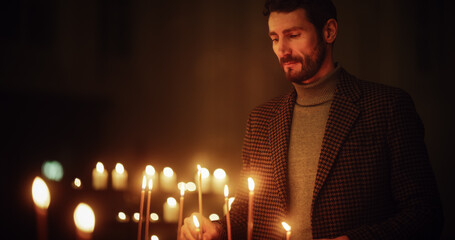 Devout Christian Man Lighting a Candle in Church, Praying and Expressing Devotion to God. Act of...