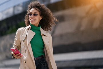 Young african woman walking outdoors carrying a suitcase and going to travel by airplane at modern airport. Vacations, travel and active lifestyle concept    