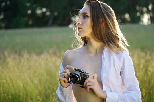 Gorgeous woman taking pictures with vintage photo camera in nature on a sunny summer day	