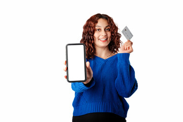 Naklejka premium Young woman smiling confident standing isolated over white background shows the camera blank white mockup screen of the phone and holds a credit card in the other hand. Smiles looking at the camera.