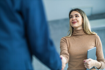 Smiling businesswoman shaking hands with a coworker during a meeting - Powered by Adobe