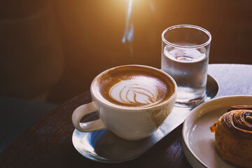 Hot coffee latte with latte art milk foam in cup mug and Homemade Raisin Danish white plate on wood desk on top view. As breakfast In a coffee shop at the cafe,during business work.