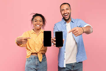 We like this app. Happy couple showing two smartphones with black screens for mock up, pointing at devices