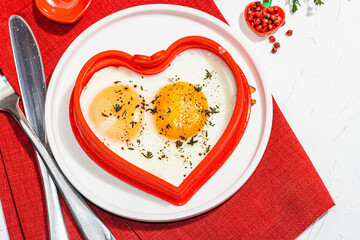 Heart-shaped fried egg served with toasted bread. Romantic art food idea for Valentine's breakfast