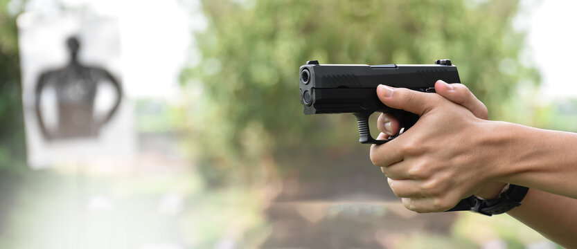 9mm pistol gun holding in right hand of gun shooter aiming to shooting target at the shooting range with copy space.