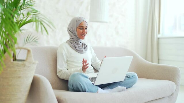 Young Muslim woman in hijab Positive female freelancer or student talking by video call on laptop computer remote communication meeting conference at home businesswoman having working conversation