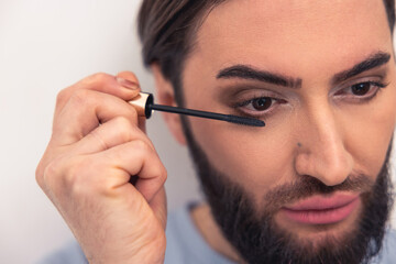 Thoughtful young man applying the eye makeup