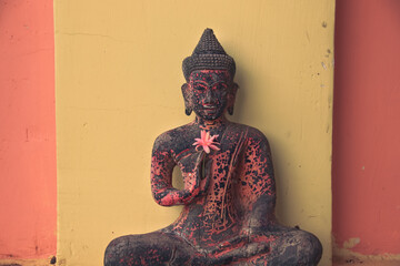 Buddha statue with a pink flower showing the concept of mindfulness, meditation and holistic healing
