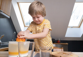The child joyfully prepares freshly squeezed citrus juice in a glass