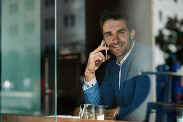 Young businessman talking on his cellphone inside of a cafe