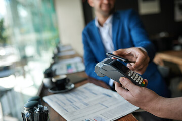 Waiter and customer using nfc technology in a cafe