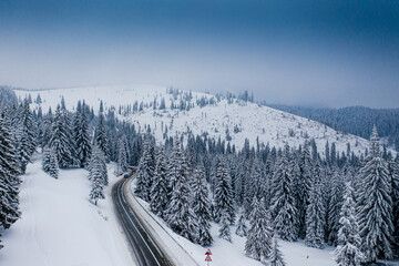 Fototapeta na wymiar Amazing winter road through a forest covered with snow, aerial view over a beautiful landscape.