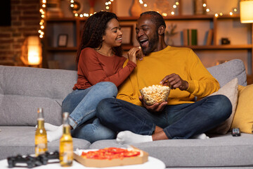 Loving pretty black woman feeding her man with popcorn