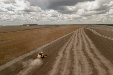 Obraz premium drone view of a tractor on the field and clouded sky