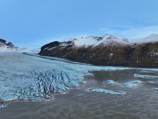 Glaciers cascade down snow-capped mountain canyons and plains carved by volcanic activity.