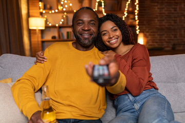 Family portrait of loving black couple watching TV at home