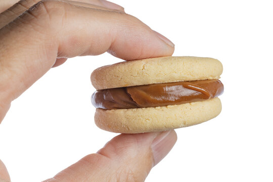 Hand holding an alfajor with dulce de leche., traditional sweet from Argentina.