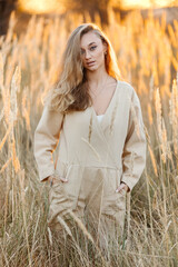 A sexy woman in a field at sunset illuminated by a yellow ray of the sun