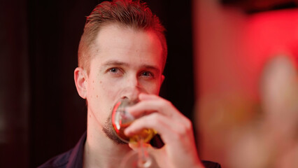 Man looking into camera while drinking wine on Valentine's Day date at home