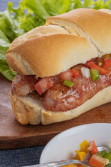 Close up of a choripan, typical argentine sandwich with chorizo and creole sauce.