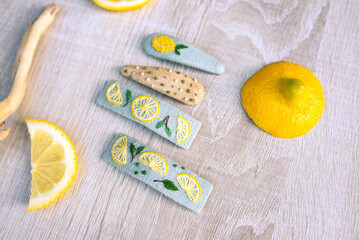 Snap hair clips with embroidered lemons on wooden background wit
