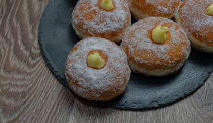 Homemade fried donuts filled with custard and seasoned with a veil of sugar
