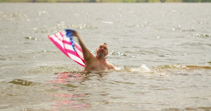 An american traveler pulled the us flag out of the water by flying it over his head. Swim in the water. Tourist