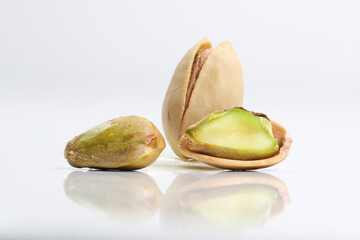 Close up of three roasted salted pistachio nut in shell on white whit reflection