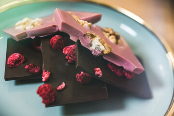 Obraz na płótnie Canvas Broken bars of premium craft chocolate with dried raspberry and walnuts. High quality photo