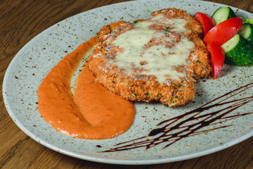 Chicken chop in batter and sauce in a plate with fresh vegetables