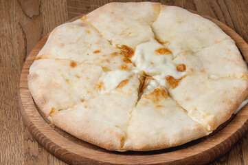 Georgian dish khachapuri with filling lies on a wooden board