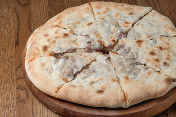 Georgian dish khachapuri with filling lies on a wooden board